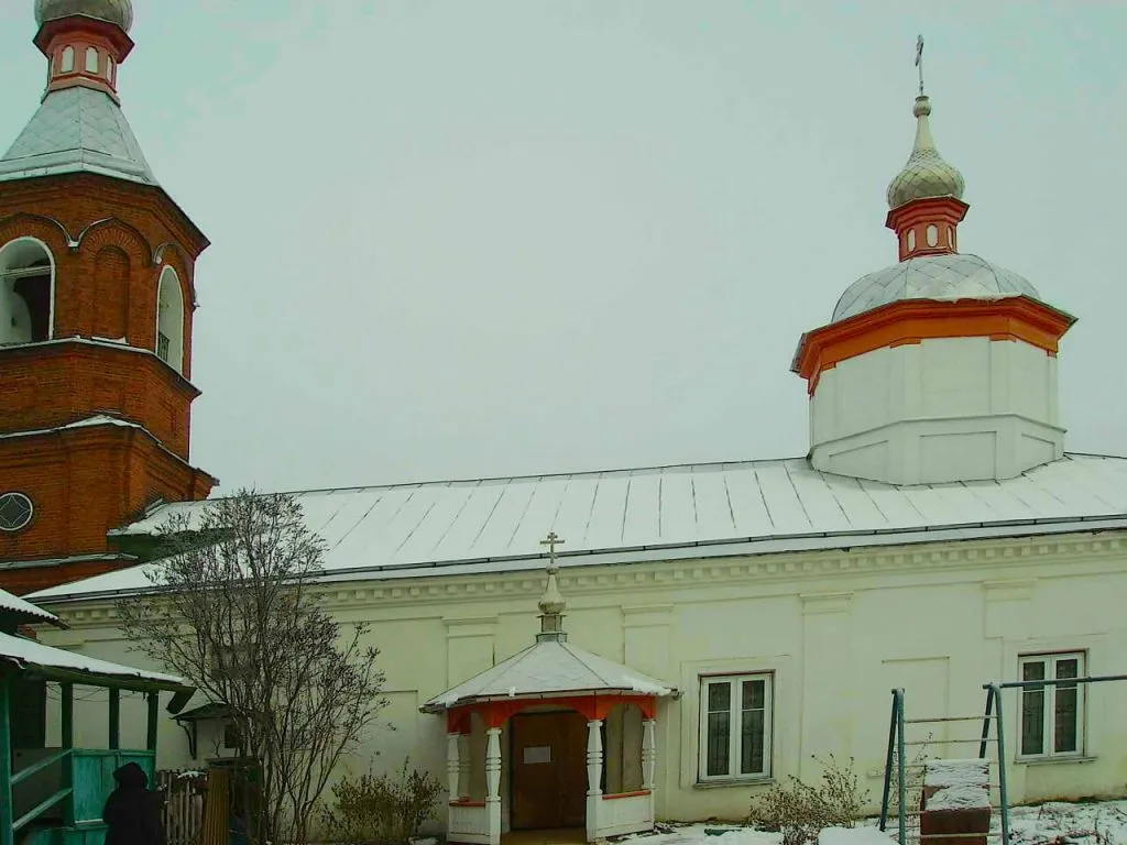 вечерняя церковь в Подмосковье зимой, белая и кирпичная, церковный дом у церкви, снежный двор, пасхальное украшение, спокойная атмосфера, религиозное место, архитектура православной церкви, зимний пейзаж, духовное настроение.