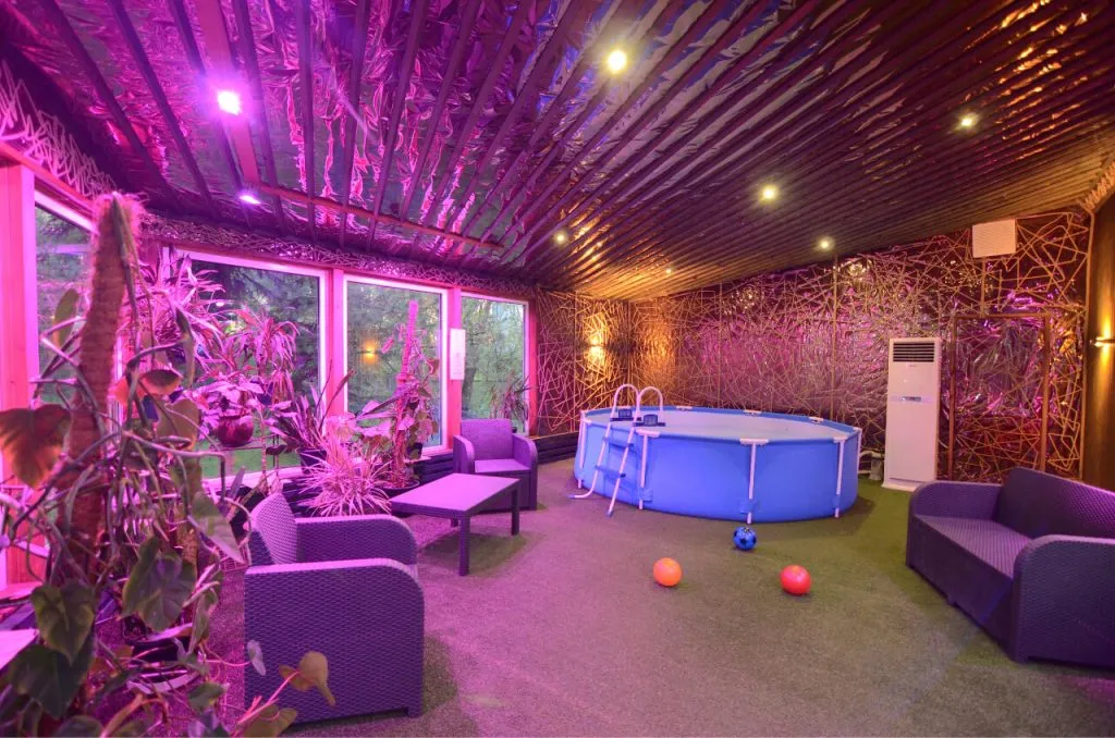 уютная зона отдыха с мягкими креслами, ярким освещением и бассейном внутри арт-отеля в Подмосковье.