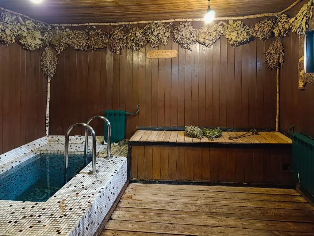 Уютная парная с дровяной бочкой из мозаичной плитки и сухой веник, стены и потолок украшены сушеным чесноком и травами. Атмосфера для полноценного отдыха и банных процедур.