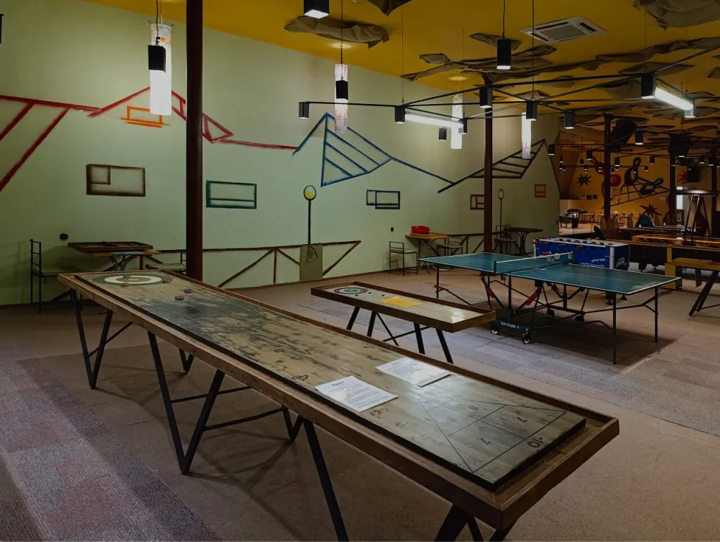 Современная игровая зона в арт-отеле ВЕ Art Resort, включающая настольный теннис и другие развлечения, ярко окрашена и уютна для отдыха и развлечений гостей.
