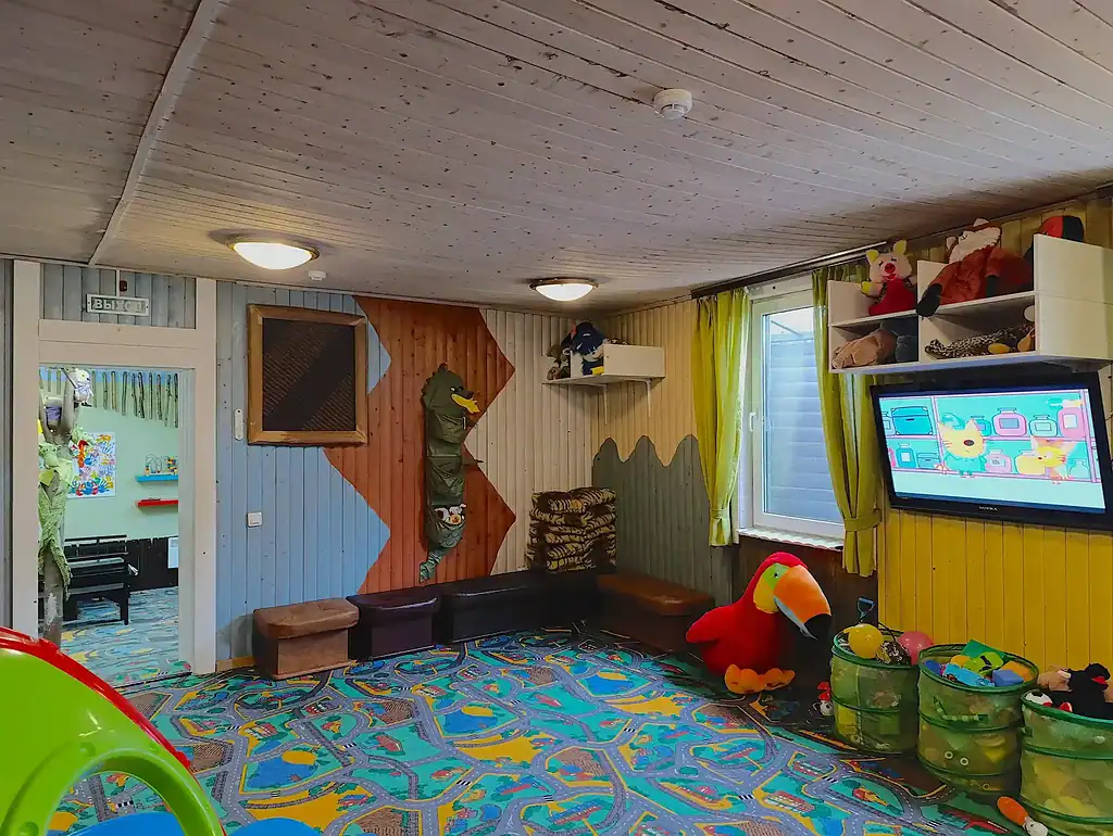 Яркая детская игровая комната с мягким ковром, игрушками, мультимедийным экраном и веселым декором, расположенная в арт-отеле ВЭ Art Resort в Подмосковье.