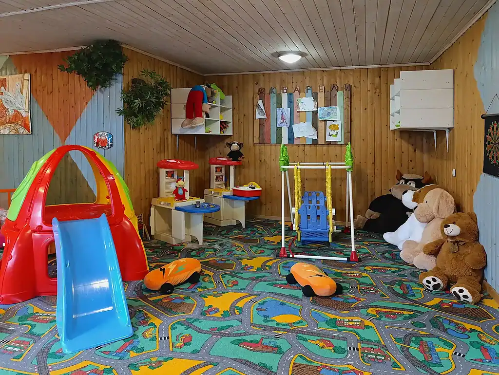 Красочная игровая комната для детей в арт-отеле ВЕ Art Resort в Подмосковье, с мягким ковром, игрушками, качелями и развивающими игрушками для комфортного отдыха всей семьи.