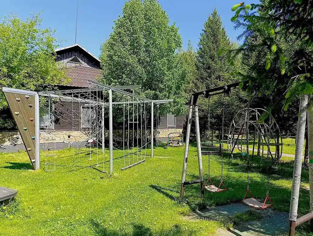 детский игровой комплекс на свежем воздухе в зеленом саду, окруженном деревьями, для отдыха и развлечений детей у отеля ВЕ Art Resort в Подмосковье.