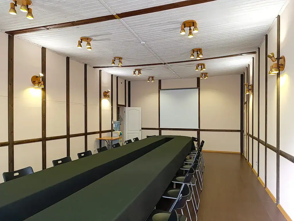 Комната для встреч и мероприятий с длинным столом, современные светильники и простое оформление, подходящая для деловых или семейных собраний в ВЕ Art Resort.