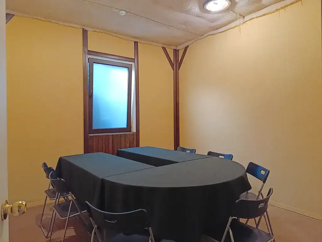 Комната с желтыми стенами, стол и стулья, окно с матовым стеклом, приятное освещение, уютное пространство для встреч и мероприятий в ВЕ Art Resort.