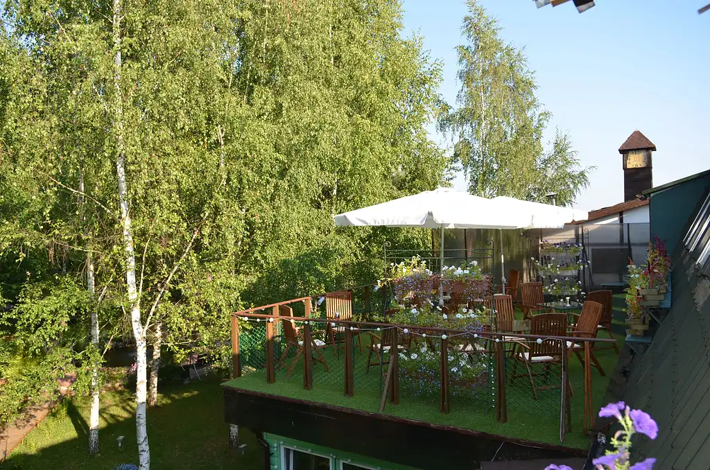 Уютная терраса на крыше с садовым мебелью и зонтом, окруженная зеленью деревьев, идеально подходит для отдыха и наслаждения природой в арт-отеле ВЕ Art Resort.