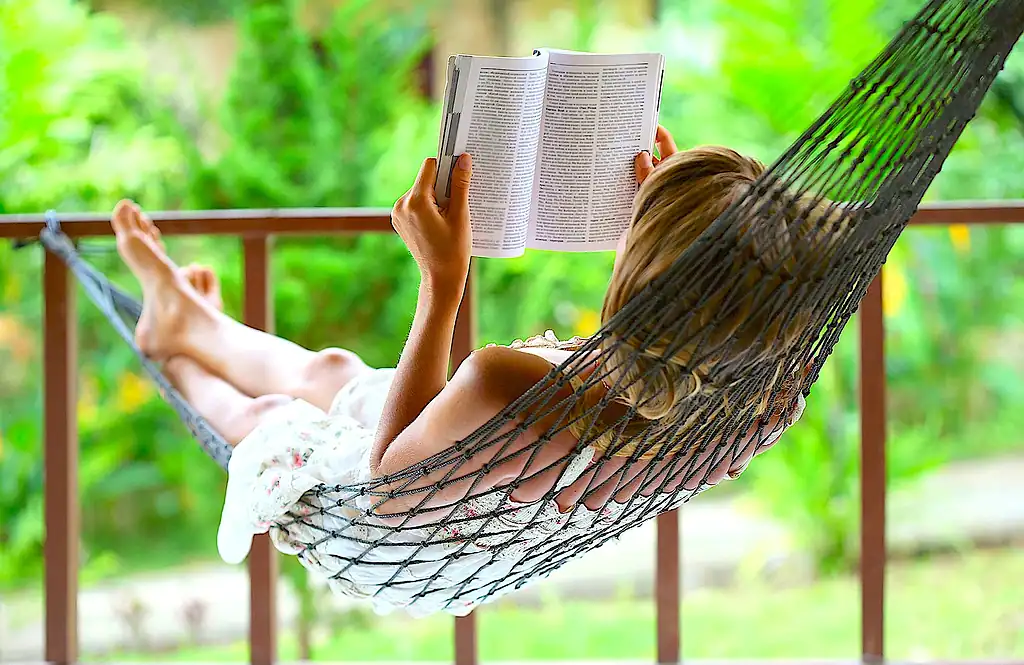 расслабляющая женщина в гамаке на природе, читает книгу на свежем воздухе, зеленый фон, летний отдых, спокойствие и гармония, отдых в Подмосковье.
