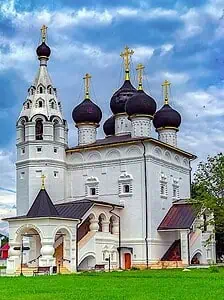 Храм с черными куполами и золотыми крестами в Подмосковье, архитектура православной церкви на фоне голубого неба и зеленых газонов.